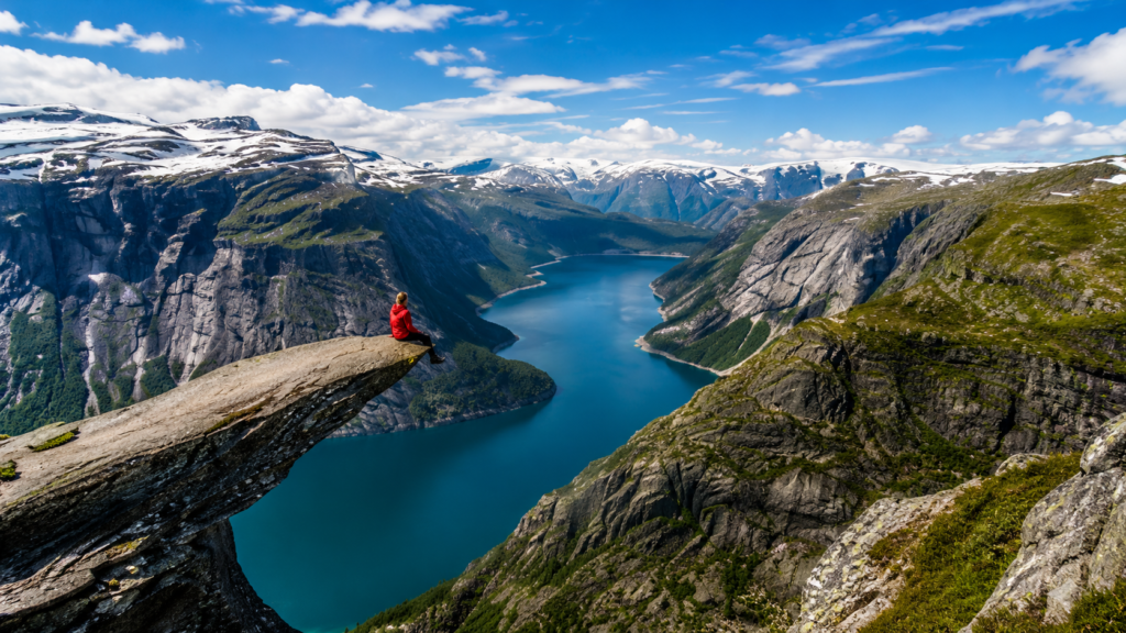 Hiker sitting on Trolltunga overlooking the spectacular Ringedalsvatnet fjord in Norway
