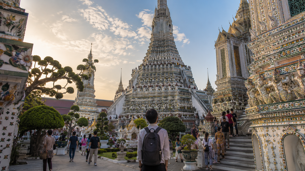 Travelers exploring the ornate Wat Arun temple complex in Bangkok during late afternoon